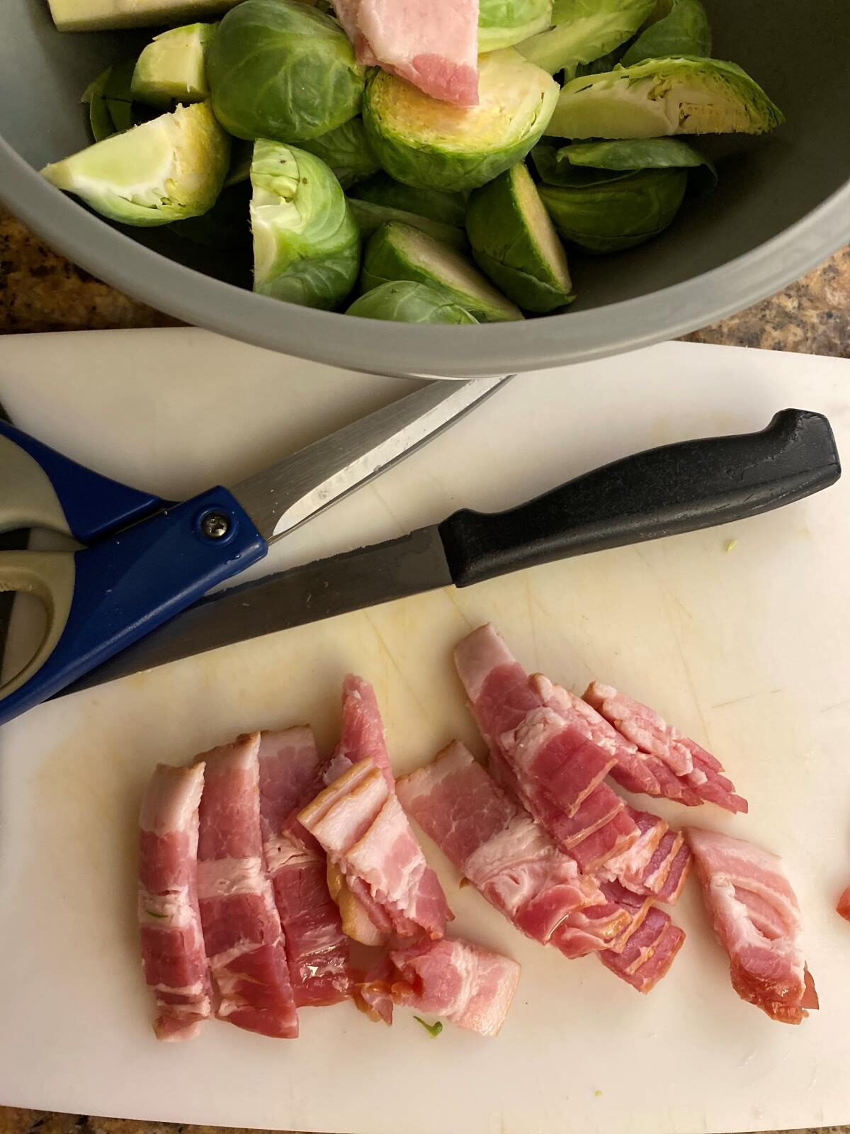 sliced bacon on a cutting board brussel sprouts in a bowl