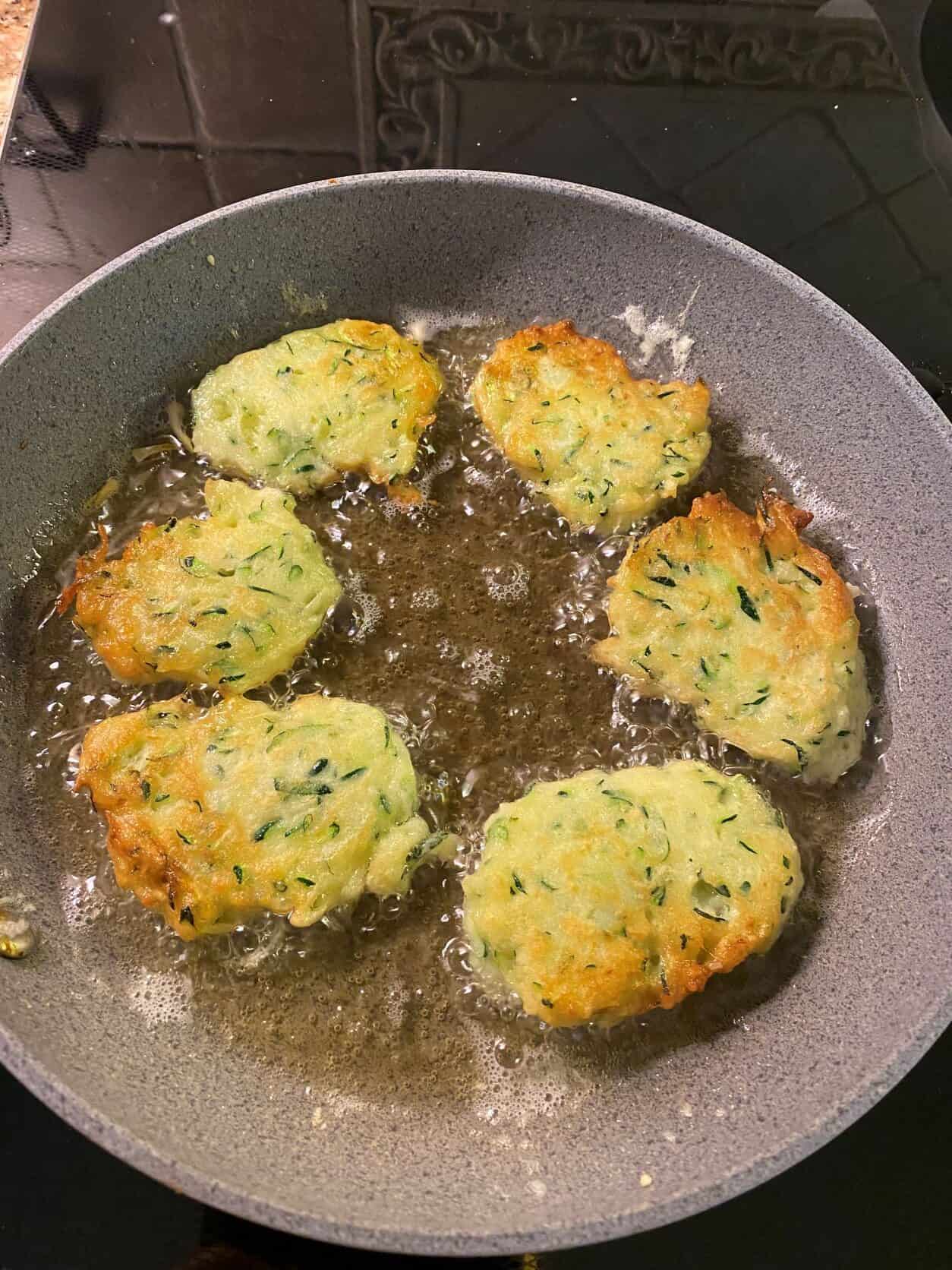 zucchini fritters frying in a pan