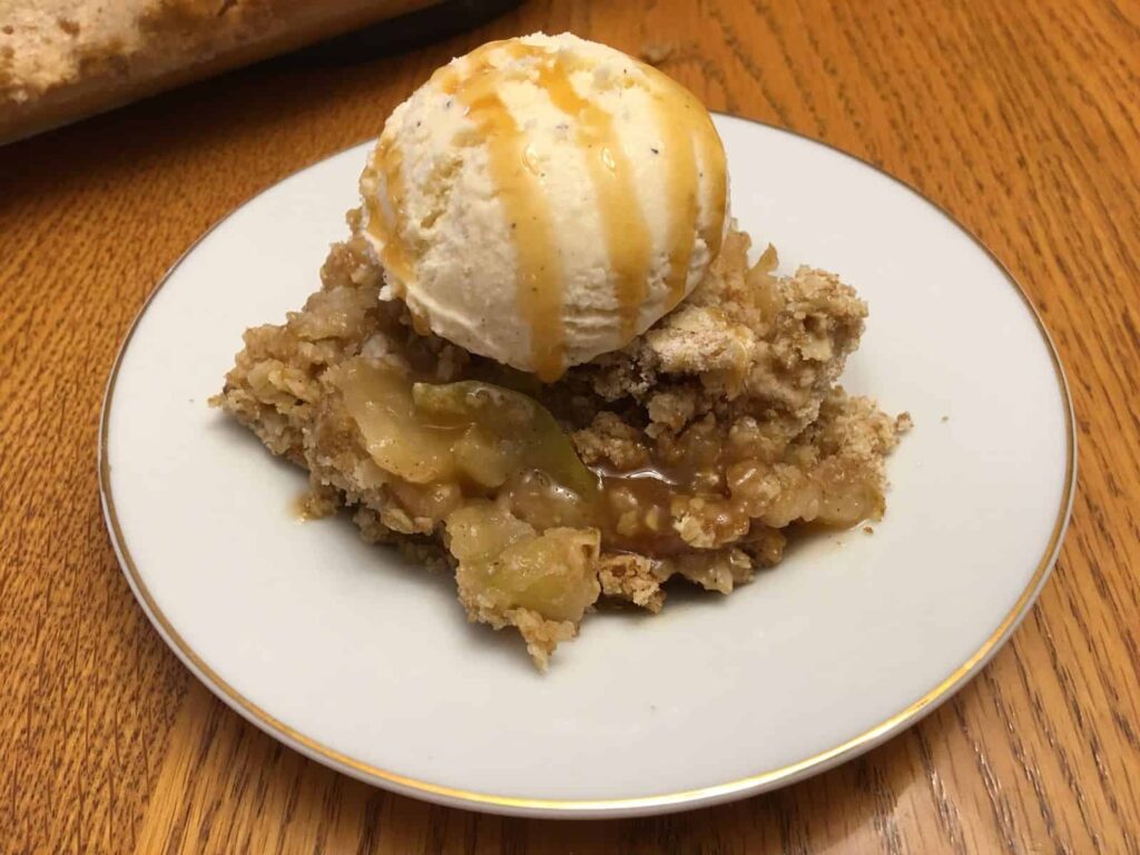 apple crisp with vanilla ice cream in a white plate