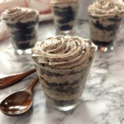 Mini dessert cups with cream cheese frosting in a glass on marble counter