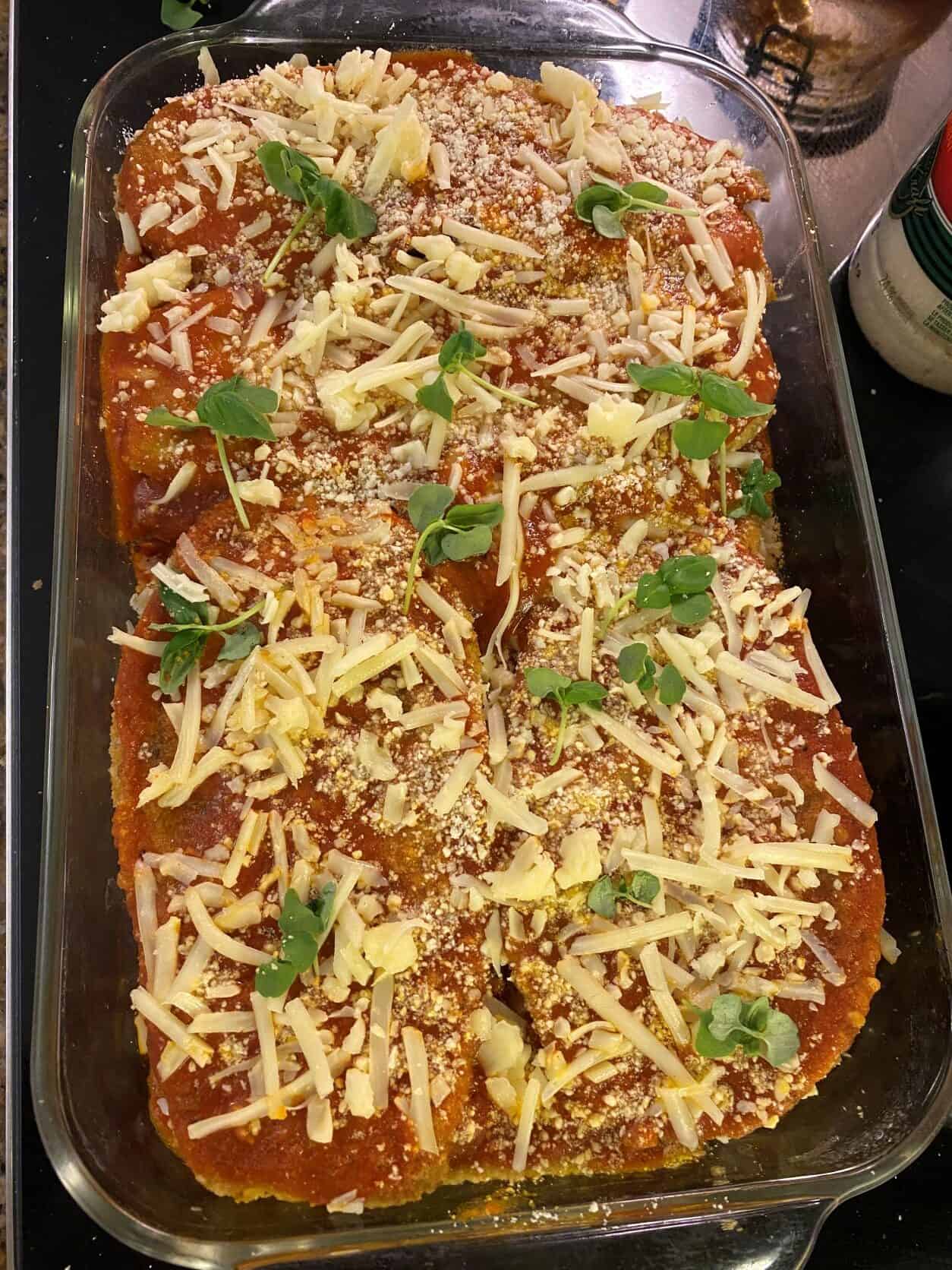 Eggplant parmesan in a baking dish with cheese and basil