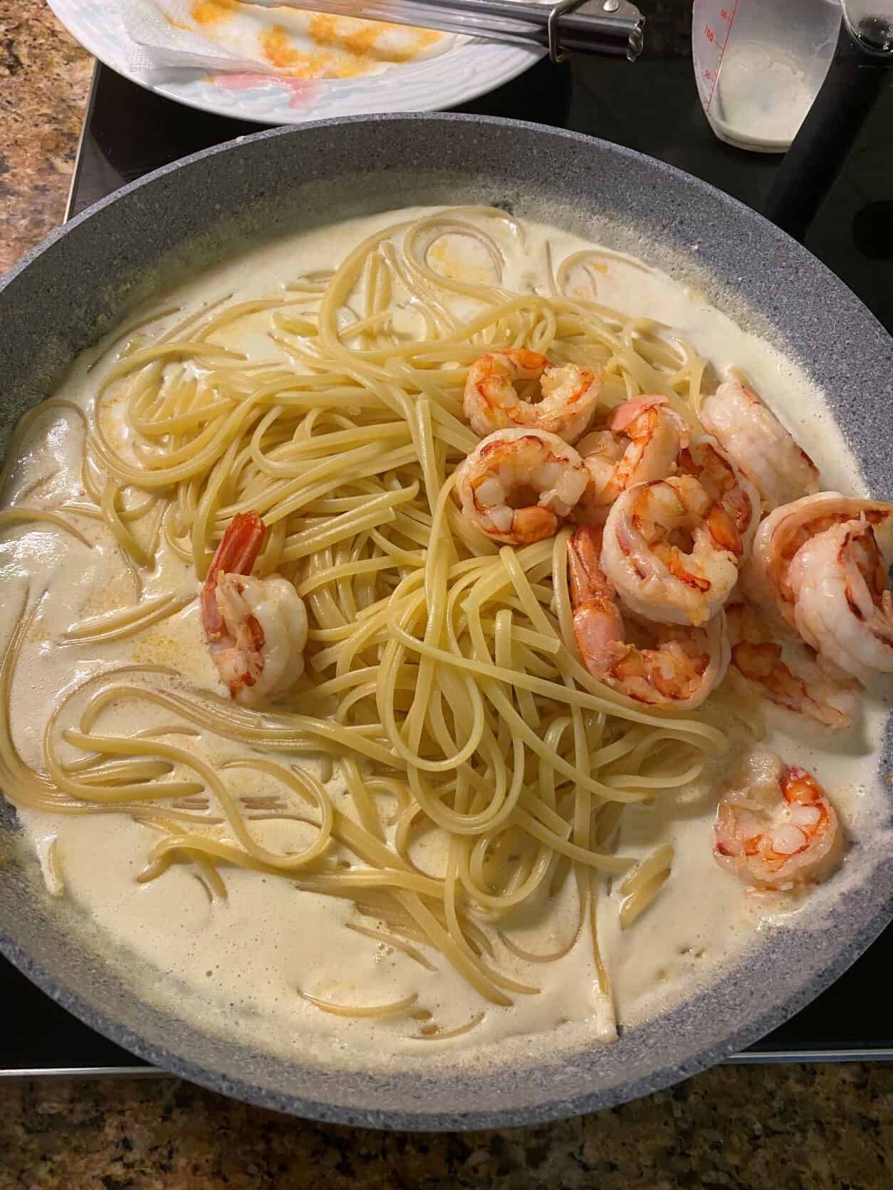 fettuccine in alfredo sauce with shrimp in a frypan