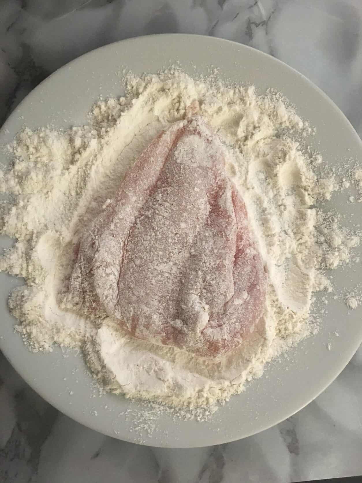 chicken dredged in flour on a white plate