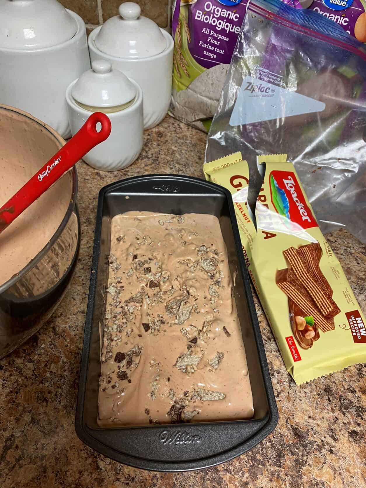 nutella ice cream in a loaf pan topped with hazelnut cookies