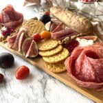 charcuterie board with cured meats crackers on wooden cutting board