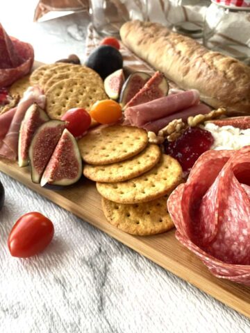 charcuterie board with cured meats crackers on wooden cutting board