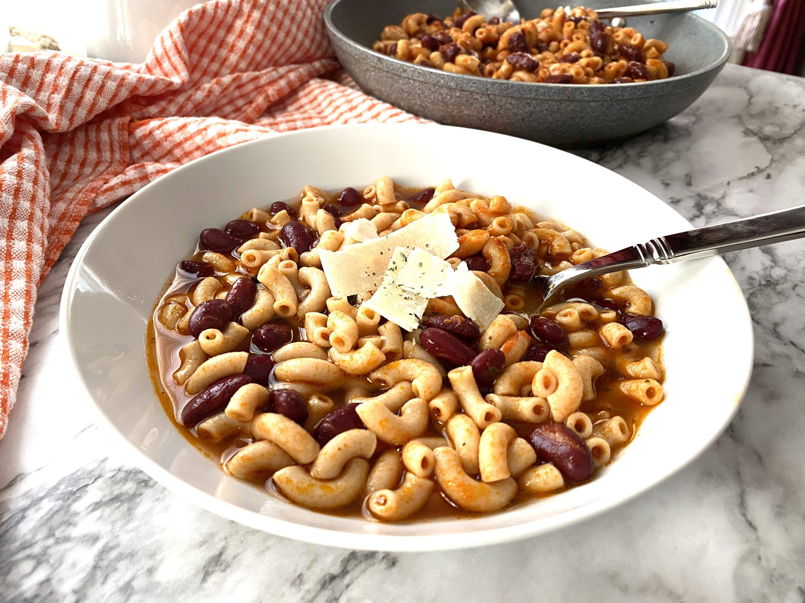 Pasta e Fagioli in a white plate with cheese