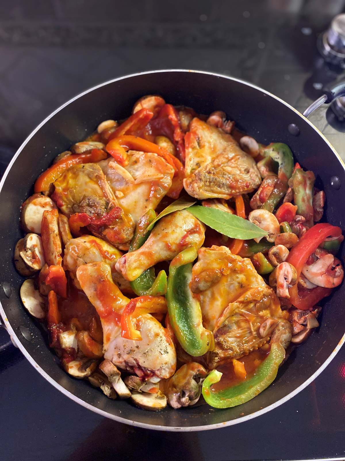 Chicken legs thighs with peppers mushrooms and sauce in a skillet