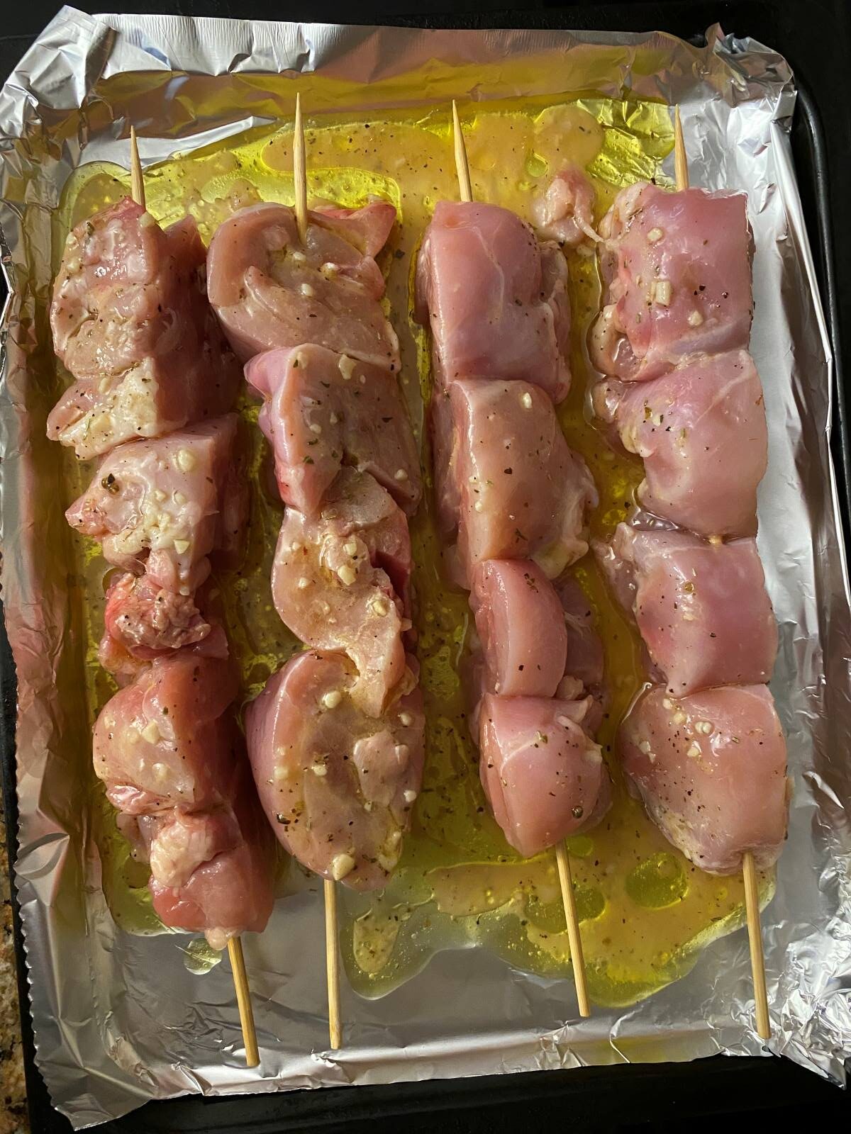 marinated chicken on 4 skewers in a baking tray
