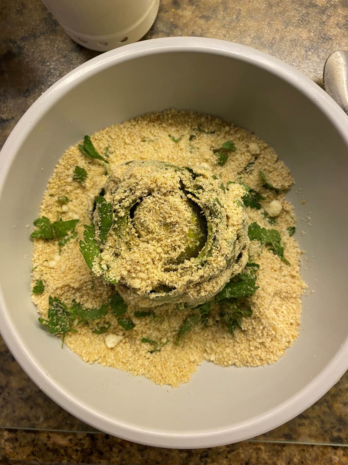 breadcrumbs, parsley, cheese, garlic and artichoke in a grey bowl