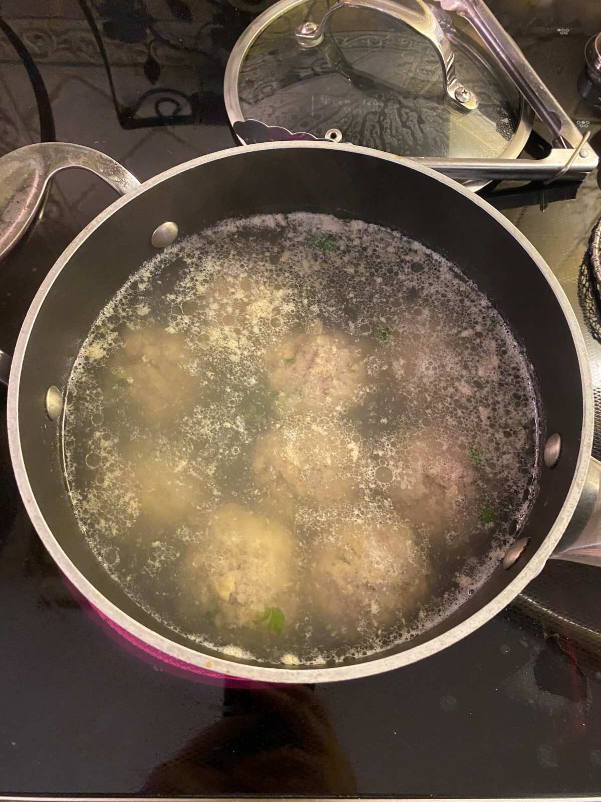 raw meatballs in a pot filled with boiling water.