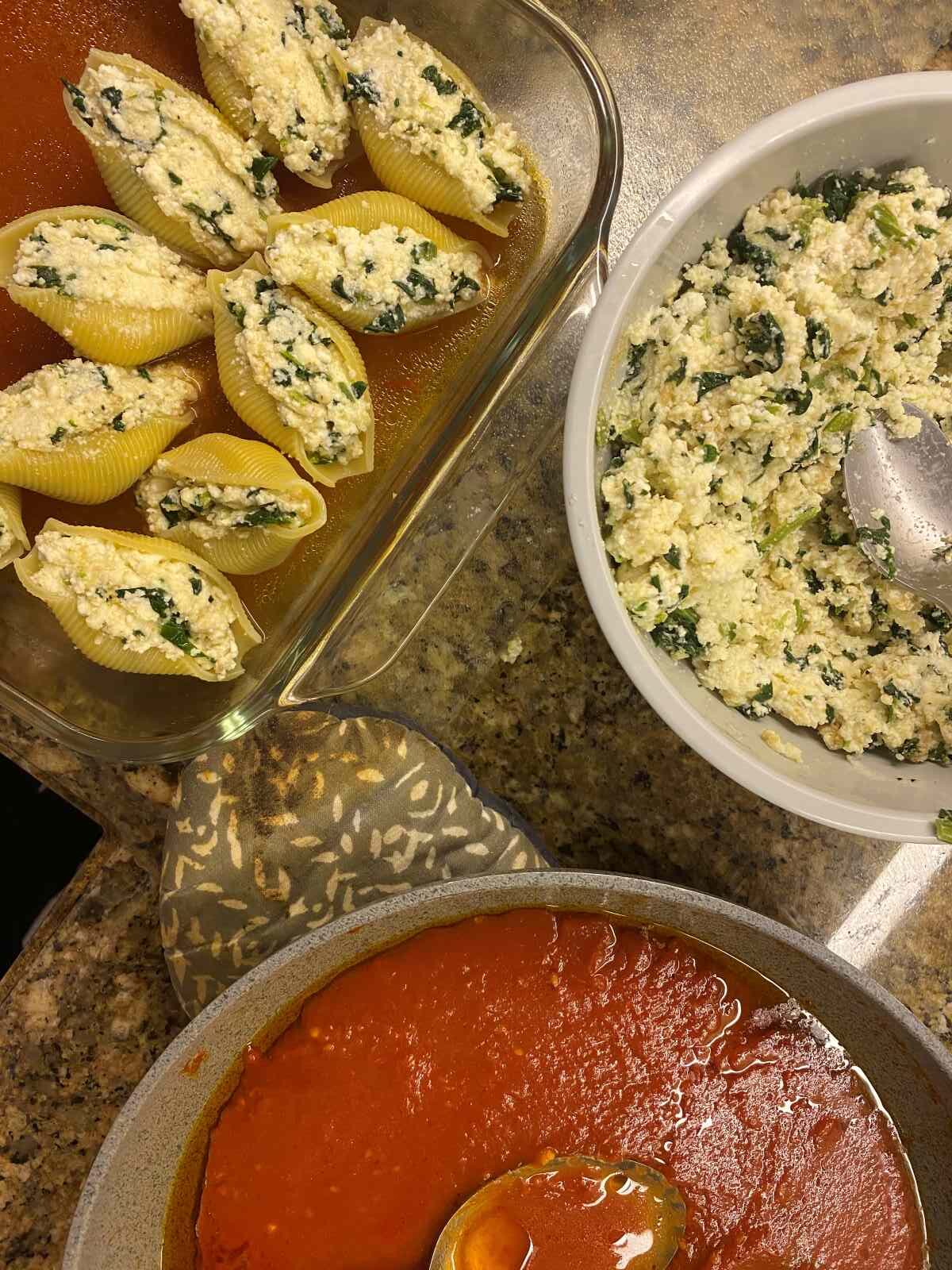 Spinach ricotta stuffing, sauce and stuffed pasta shells on the counter