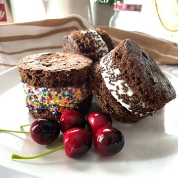 Chocolate Sandwich filled with Ice cream on a white plate with cherries