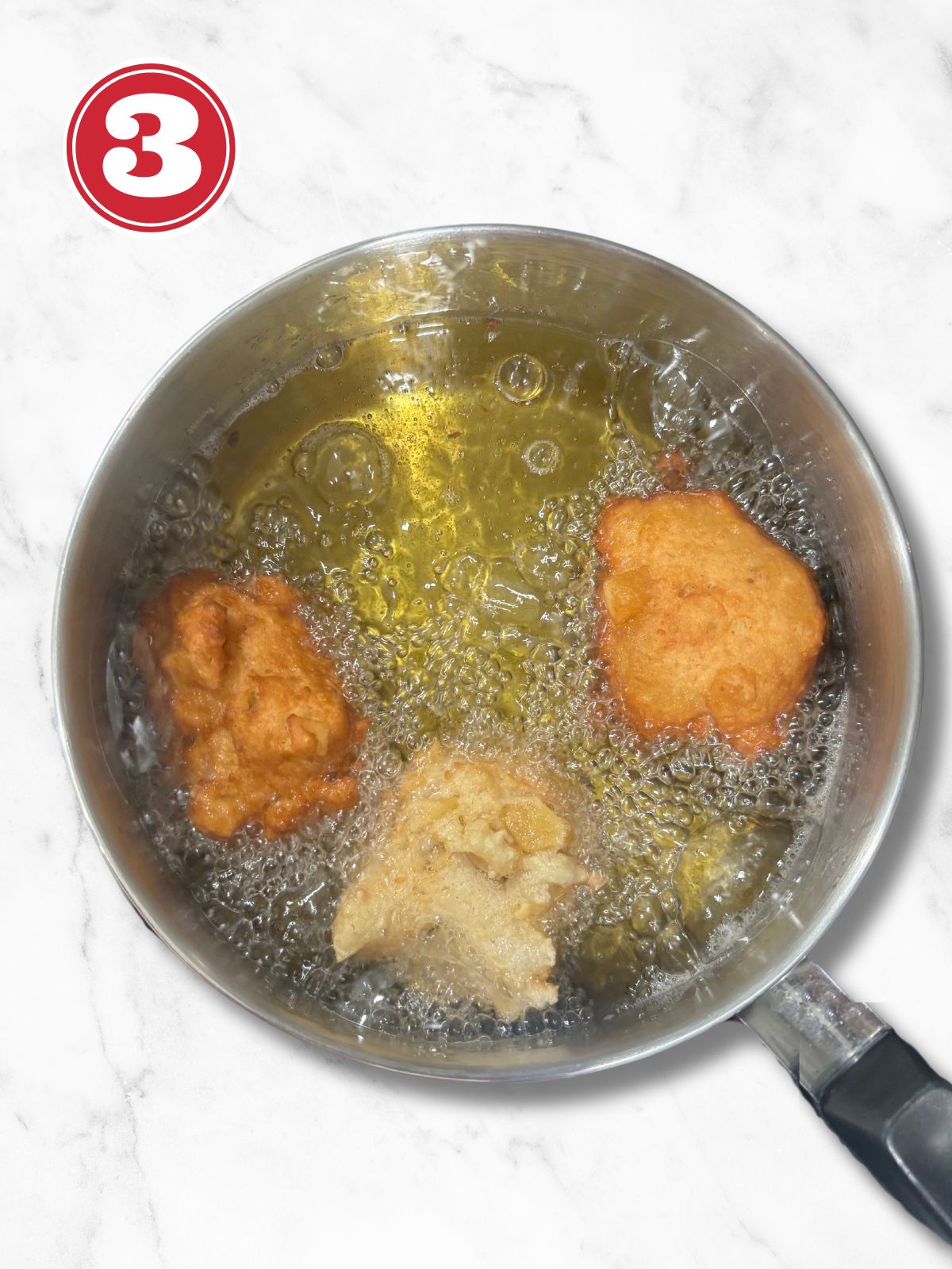 apple fritters frying in a saucepan filled with oil