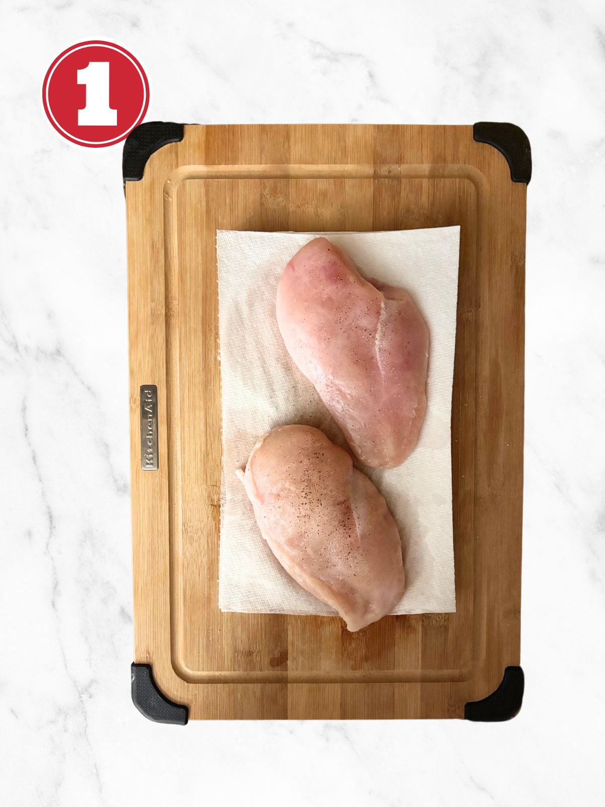 raw chicken breast on a paper towel and cutting board