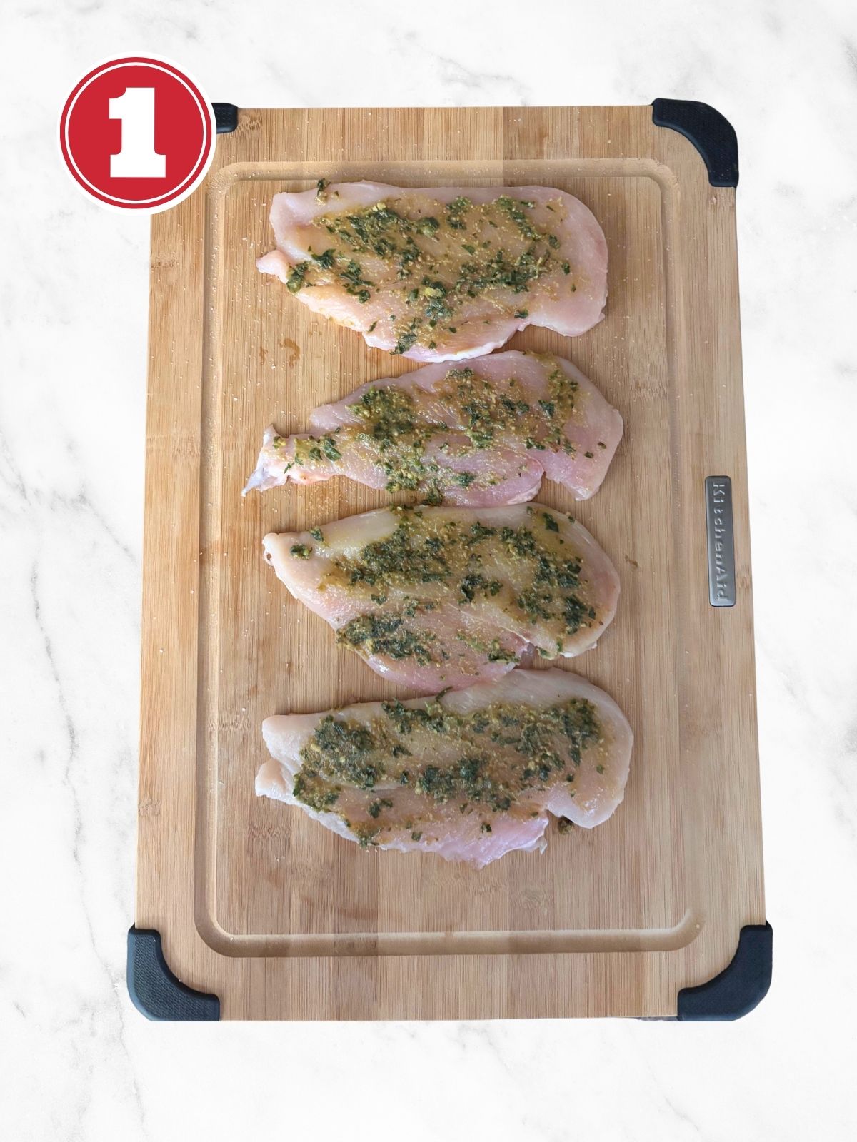 raw chicken with pesto on a wooden cutting board