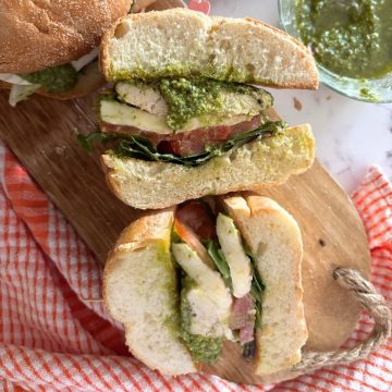 caprese chicken sandwich on a wooden cutting board