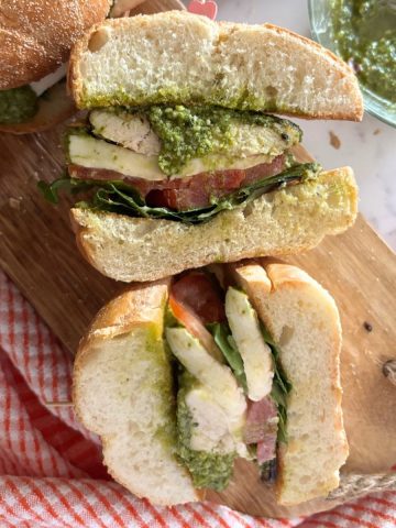 caprese chicken sandwich on a wooden cutting board