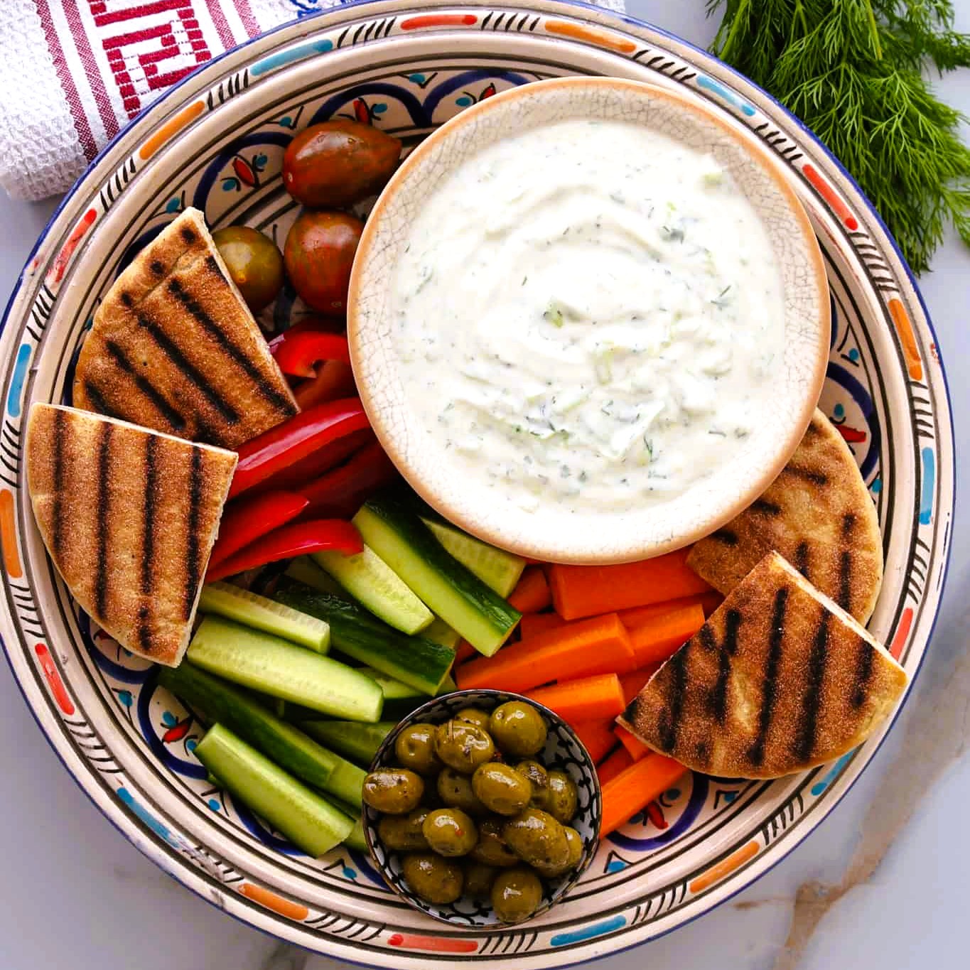 Greek Tzatziki Sauce in a plate with vegetables, pita olives
