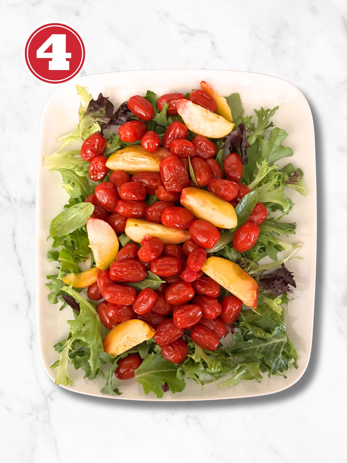 platter with greens and cherry tomatoes and peaches on top
