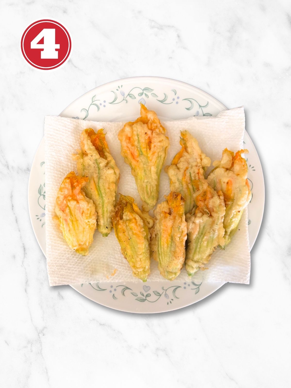 stuffed zucchini flowers on a paper towel in a white plate