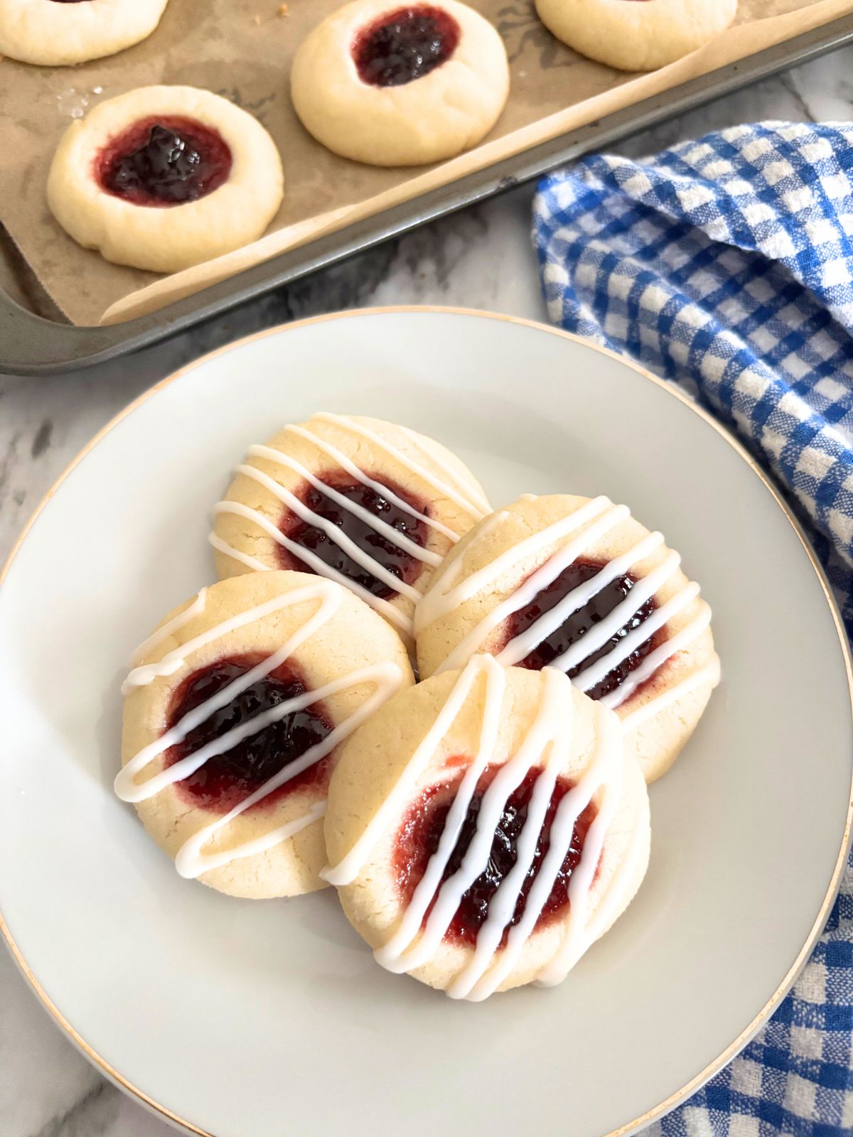 almond thumbprint cookies in a white plate with icing