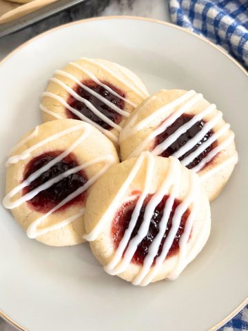 almond thumbprint cookies in a white plate with icing