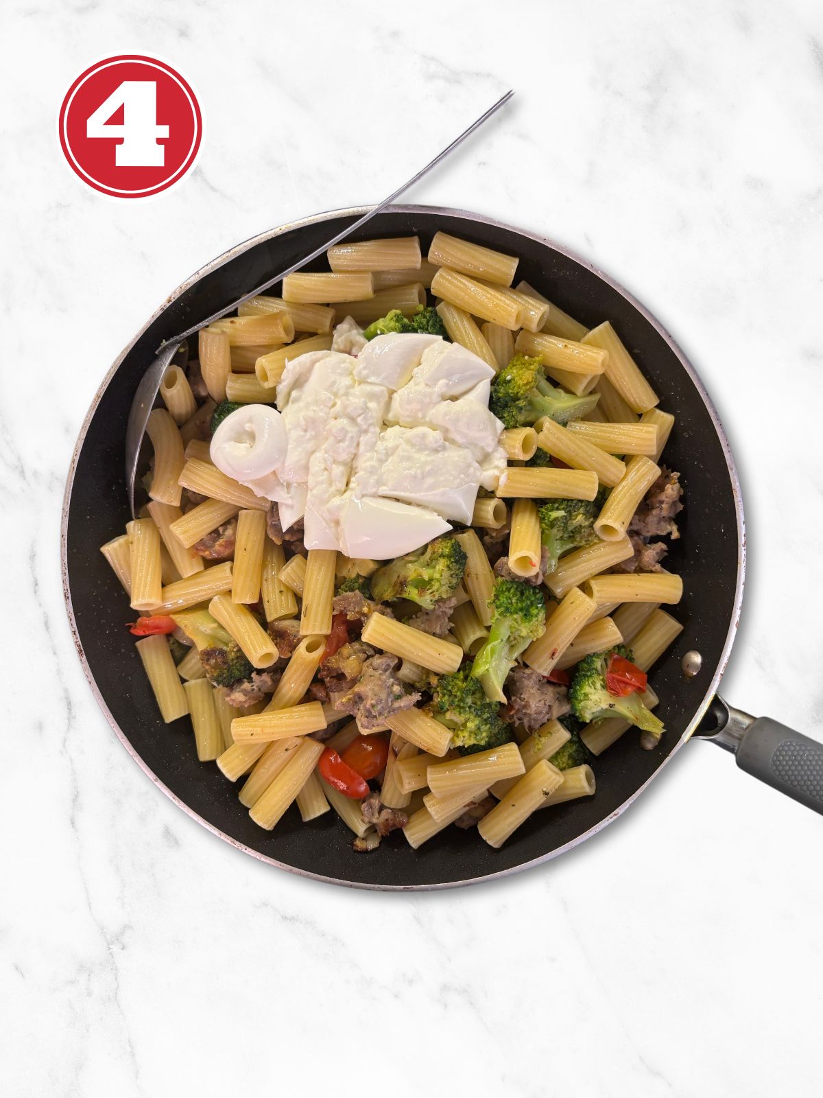 broccoli and sausage pasta with burrata on top in a skillet