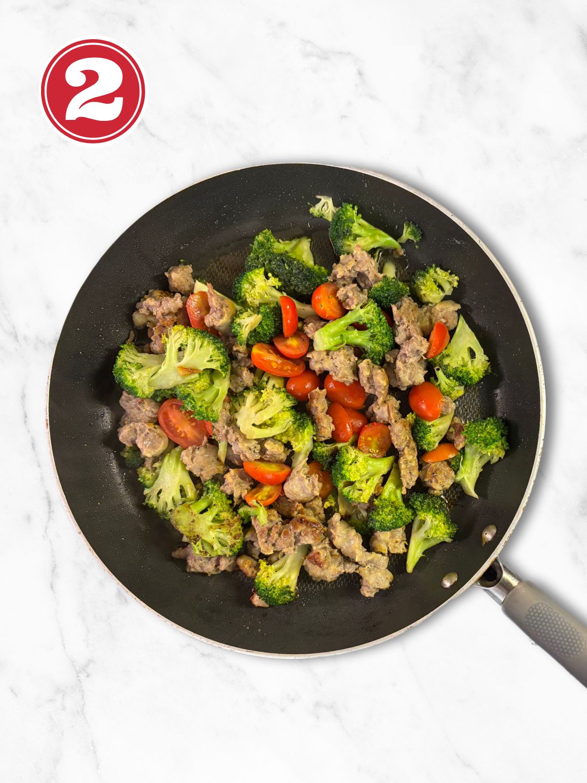 cooked broccoli, sausage and cherry tomatoes in a skillet