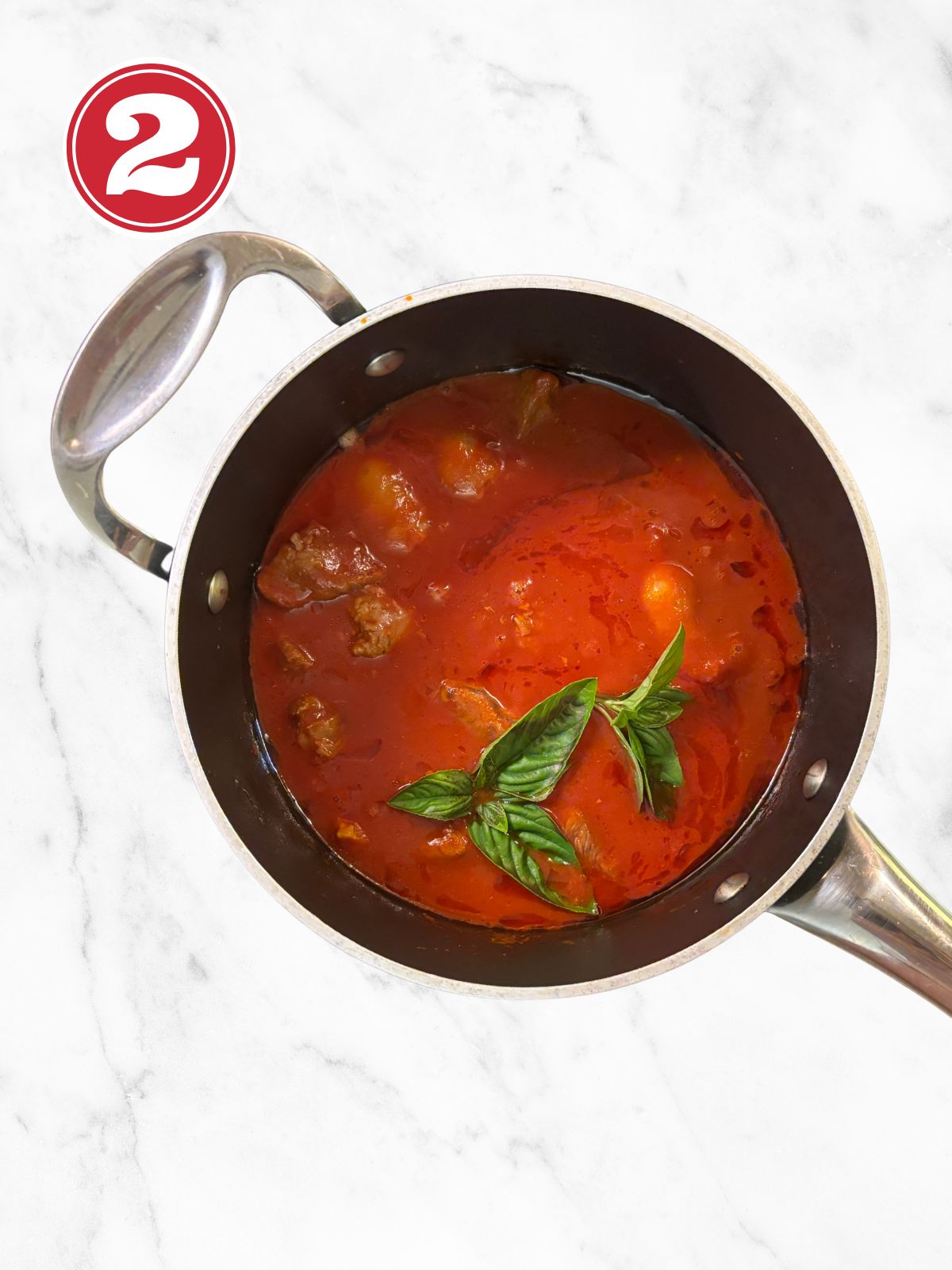 a pot with browned stewing beef, sausage tomato paste and tomato sauce
