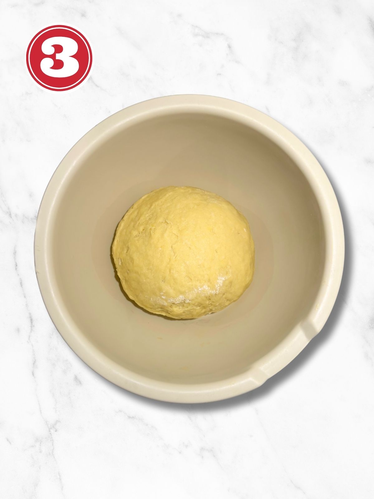 panettone dough ball in a beige bowl