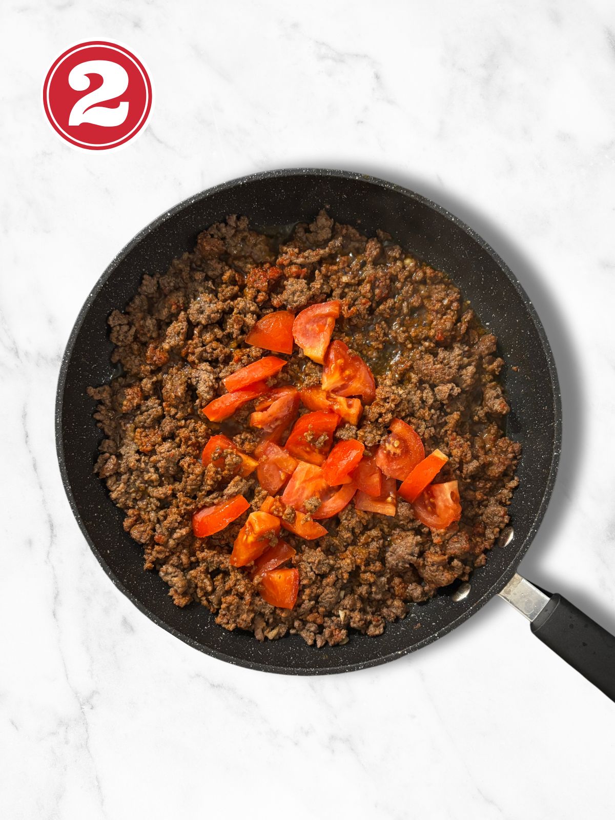 sauteed ground beef in a skillet with chopped tomatoes